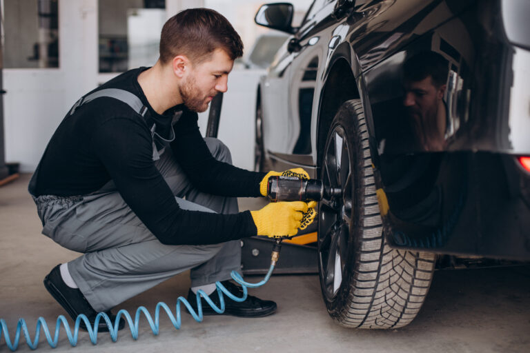 Car mechanic changing wheels in car